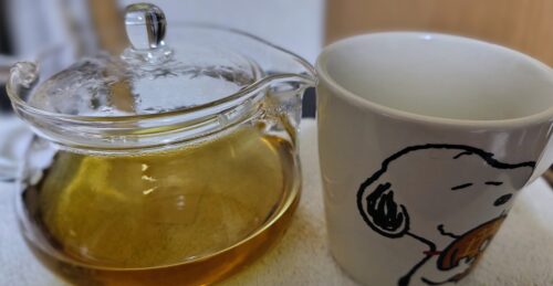 ガラスのティーポットに入った、3月に早摘みしたヨモギ茶とスヌーピーのティーカップの画像。