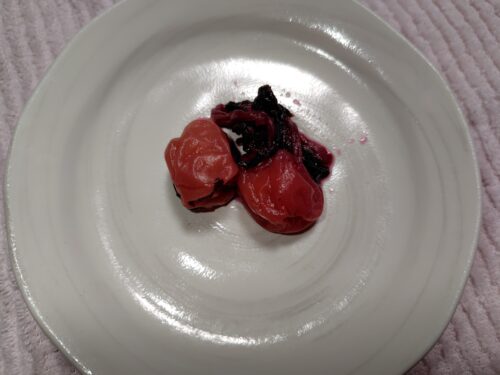 お皿に盛られた2個の梅干しと赤紫蘇の画像。